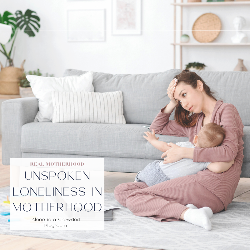 Mom sitting on the floor with baby in one arm, head in hand of other arm, leaning against couch. Tired, overwhelmed, and lonely.